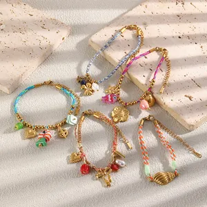 Detailed view of colorful braided 18K gold plated bracelets with charms on stone