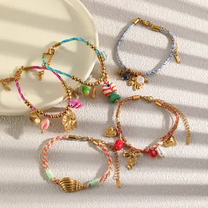 Detail view of colorful woven rope bracelets with gold-plated shell and heart charms