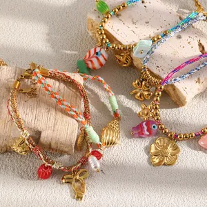 Close-up of colorful braided rope bracelets featuring 18K gold-plated bow and heart charms