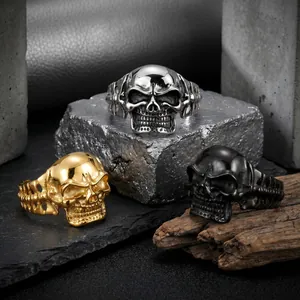 Close-up detail of three punk skull-shaped titanium steel bracelets in gold, silver and black.