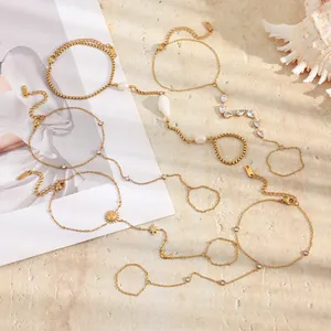 Détail de diverses chaînes de main en acier inoxydable plaqué or 18K avec coquillages.
