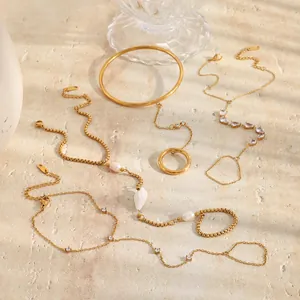 Détail de diverses chaînes de main en acier doré 18K avec conque et perles élégantes