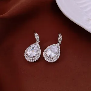 Primer plano de elegantes pendientes de gota de circonita sobre fondo marrón