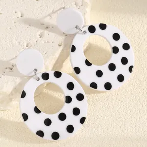 Close-up detail of retro black and white polka dot hollow circular acrylic drop earrings