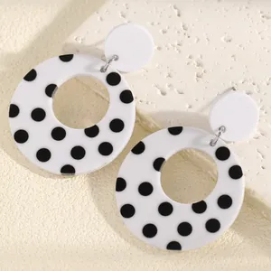 Detailed close-up of retro black and white polka dot acrylic hollow hoop earrings