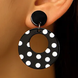 Close-up of black and white polka dot acrylic earrings showing texture and detail.