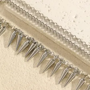 Detailopname van een zilveren punkketting met dubbele ketting en kegelvormige spikes