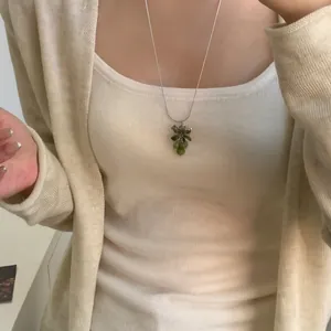 Gros plan d'un collier avec pendentif en grappe de raisin vert porté par un modèle de mode.