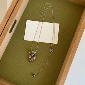Vue détaillée du collier avec pendentif grappe de raisin style ins sur fond de plateau vert