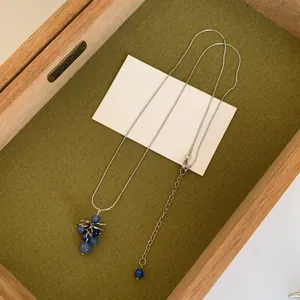 Vue détaillée d'un collier en argent avec un pendentif grappe de raisin bleue élégant.