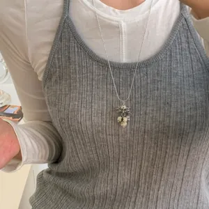 Vue détaillée d'un collier à pendentif grappe de style ins porté sur un haut gris.