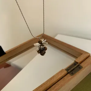 Vue détaillée d'un collier pendentif grappe de raisin avec perles marron et feuilles