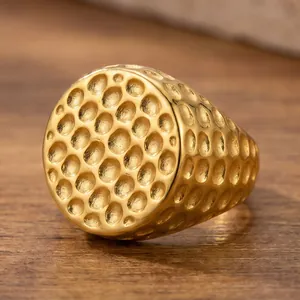 Gedetailleerde opname van een gouden roestvrijstalen herenring met gehamerde textuur