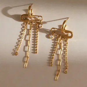 Dettaglio orecchini a spilla da balia dorati con zircone e nappe di catenelle fini.