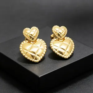 Detailed view of gold quilted double heart stud earrings in stainless steel.