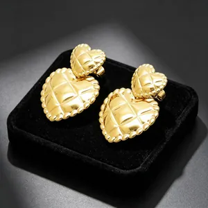Detailed macro view of gold quilted double heart earrings on a black velvet display tray.