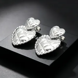 Close-up of silver quilted heart stud earrings with retro titanium steel finish