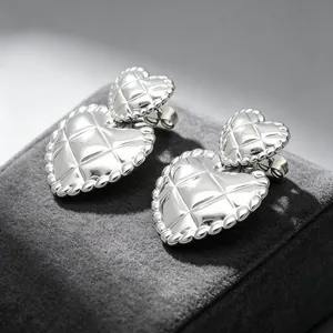 Close-up of vintage silver quilted heart earrings with rhombus pattern texture