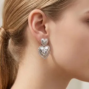 Close-up of silver quilted double heart earrings on ear for a chic vintage look