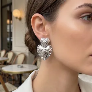 Detailed close-up of vintage quilted double-layered heart stud earrings worn by a model