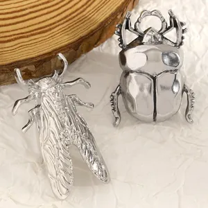 Primo piano dettagliato di spille a forma di cicala e scarabeo in argento anticato