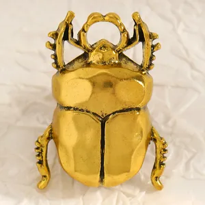 Vista dettagliata della spilla a forma di scarabeo in oro vintage con trama in metallo.
