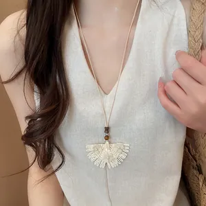 Detailed view of a handmade woven rattan skirt pendant necklace worn by a model