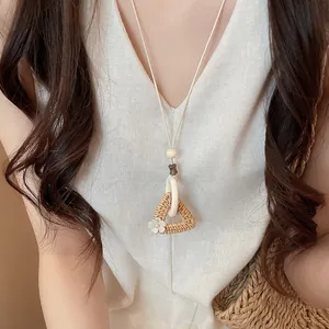 Close-up view of a handwoven triangle pendant necklace with a delicate white floral accent