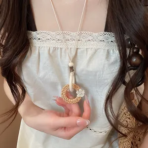 Close-up of bohemian style woven rattan circular pendant necklace worn by female model