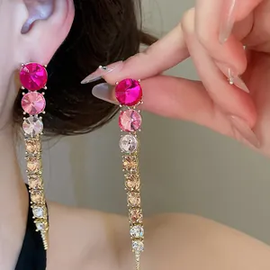 Macro detail showing the gradient pink and amber crystal sequence on long tassel earrings