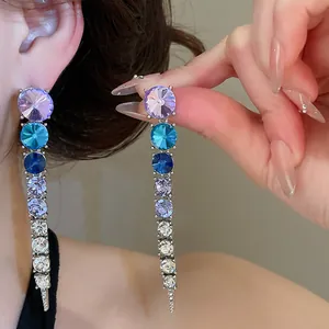 Close-up detail of long tassel dangle earrings featuring gradient blue and purple crystals