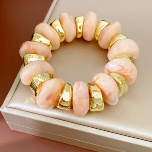 Detail van marmeren acryl kralen en gouden metalen tussenstukjes op een stretch armband.