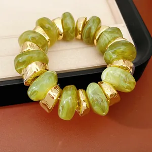 Detailweergave van groene marmeren acryl kralen en gouden afstandhouders op de armband