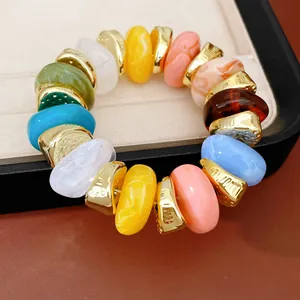 Detail van kleurrijke acryl kralen en gouden spacers op een rekbare elastische armband