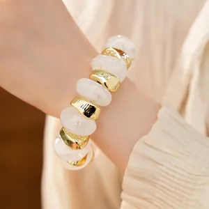 Detailopname van een elastische armband met onregelmatige geometrische kralen van acryl en goud