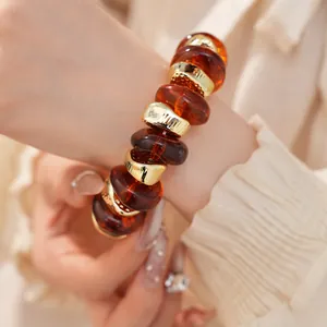 Detailweergave van een elastische armband met barnsteenkleurige acryl kralen