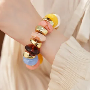 Detail van een kleurrijke elastische armband met onregelmatige acryl kralen om de pols gedragen