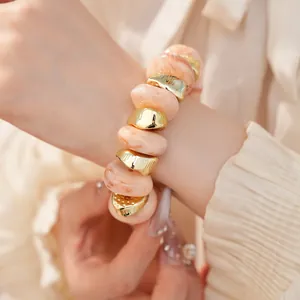 Gedetailleerde macro-opname van een elastische armband met acrylmarmer en gouden kralen