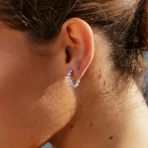 Detail of stainless steel hoop earring with round white cubic zirconia on ear