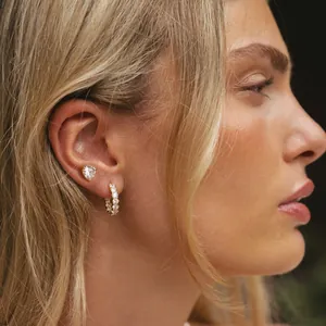 Detailed view of elegant heart stud and golden sparkling crystal hoop earrings on model