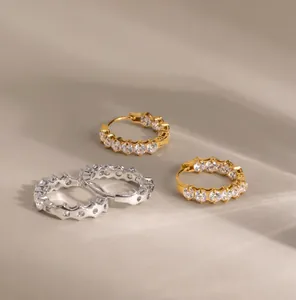 Detailed macro view of gold and silver stainless steel hoop earrings with zircons