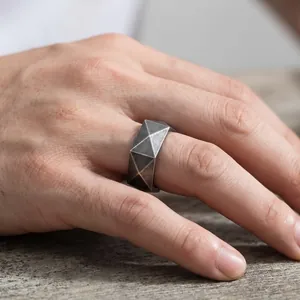 Nahaufnahme eines minimalistischen Edelstahlrings mit facettiertem geometrischem Design.