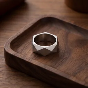 Nahaufnahme eines minimalistischen, geometrischen Edelstahlrings auf einem dunklen Holztablett