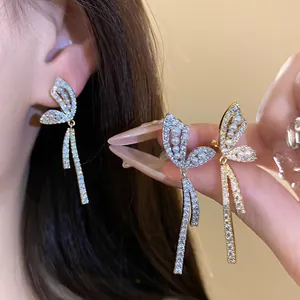 Primo piano di eleganti orecchini a clip a farfalla con zirconi e perle, effetto indossato.