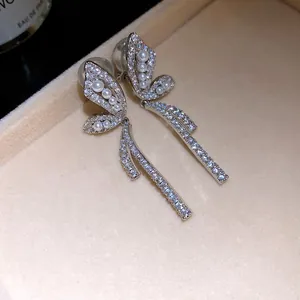 Dettaglio di orecchini a clip a farfalla placcati oro 18k con perle e zirconi