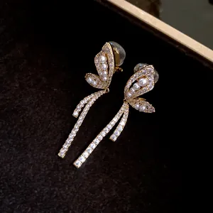 Dettaglio macro di orecchini a clip a farfalla placcati oro 18k con zirconi e perle