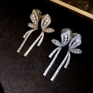 Vista dettagliata degli orecchini a clip a farfalla in oro 18k con perle e cristalli.