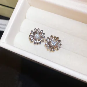 Primer plano detallado de pendientes de flores bañados en oro de 18k con circón central