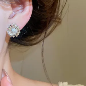 Primer plano de un pendiente de flor de circonita bañado en oro de 18 quilates en la oreja