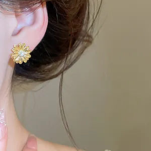Primer plano de pendientes de flor bañados en oro de 18k con circón en la oreja
